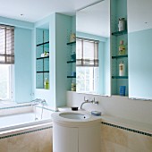 Bathroom with turquoise-painted walls, shelving in niches, mirrors and cylindrical washstand