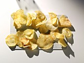 Kartoffelchips auf Küchenbrettchen liegend (Aufsicht)