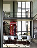 Open-plan interior with dining table, English telephone box as decoration & staircase leading to gallery