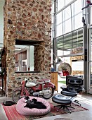 Seating area with leather armchair and beanbag; vintage motor scooter as ornament in front of stone wall with integrated fireplace