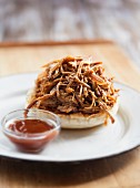 Pulled Pork Piled on a Bun with a Side of Barbecue Sauce