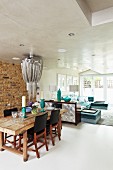 Open-plan interior with eclectic mixture of styles in dining area and modern living area; sideboard with stainless steel front used as partition