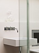 Rectangular, white washbasin with shiny, wall-mounted tap fittings