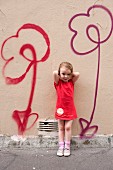 Little girl standing in front of flower motifs spray-painted on wall
