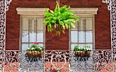 Fenster an einem Balkon mit Blumen und ornamentalem Gitter