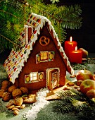 A gingerbread house surrounded by nuts and apples