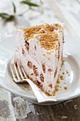 A slice of ice cream torte with nut brittle on a plate