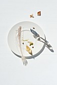 Fish bones from a sole and a lemon wedge on a plate with fish knife and fork