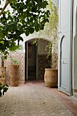 Idyllischer Innenhof eines marokkanischen Hauses mit Pflanzen in handgefertigten Tontöpfen und Mosaikfliesen an Boden und Wänden