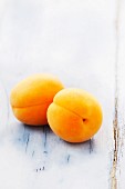 Two apricots on a wooden surface