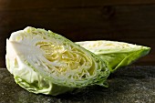 A pointed cabbage, halved, on a stone slab
