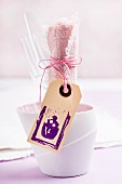 Plastic cutlery and pink linen napkin in beaker; wooden tag with rubber-stamped cake