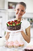 Junge Frau präsentiert Erdbeer-Schoko-Torte