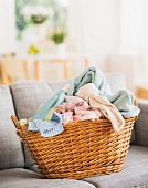 Dirty laundry & bottle of laundry detergent in basket on sofa