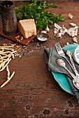 An arrangement of cheese, pasta, garlic and cutlery