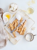 Small savoury breadsticks on a board, ingredients alongside