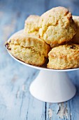 Home-made scones on a white cake stand on a blue wooden surface