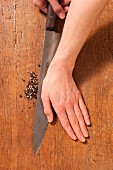 A hand crushing spices with a knife blade