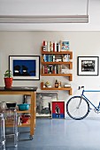 Island kitchen counter on castors and designer, plexiglass stools (Ghost); various artworks, bookshelves and racing bike against wall in background
