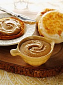 Schale mit einer cremigen Cashew Butter auf einer hölzernen Platte dazu Englisch Muffins.