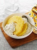 Bowl of large curd cottage cheese with pineapple slices on a serving board with yellow napkin