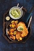 Wiener Schnitzel (breaded veal escalope from Vienna) with fried potatoes and a cucumber salad