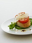 Grilled tomato on bruschetta with parmesan on a bed of spinach