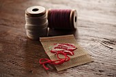 Embroidery sample and reels of yarn on rustic wooden surface