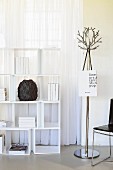 White shelving unit in front of window next to metal coat rack