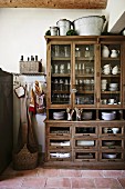 Old kitchen cupboard with glass-fronted upper section and terracotta floor in rustic ambiance