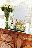 Perfume bottles on tray and romantic mirror with decorative frame on antique dressing table