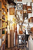 Sammelsurium aus Stoffrollen, Bildern an der Wand und Zweigen in Vase vor Regal