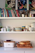 Wooden boards on kitchen base unit below books and crockery on shelves below film posters