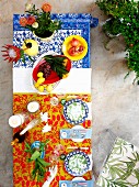 Farbenfrohe Stimmung auf dem Tisch - Blick von oben auf bunte Gedecke und tropische Blumen in Vasen