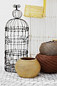 Old, ornate bird cage and various round baskets with wire rack in background