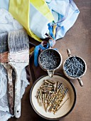 Still-life of paintbrushes, nails, screws & decorative fabrics