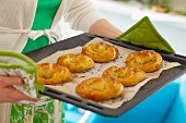 Woman holding baking tray with freshly baked yeast pretzels
