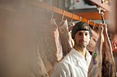 A butcher among hanging cuts of meat
