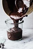 Chocolate sauce being poured into a jar