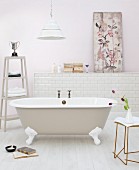 Free-standing, nostalgic bathtub and side table; picture leaning against wall on masonry shelf in background