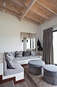 Masonry corner bench with scatter cushions on grey seat cushions and pair of grey ottomans