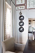 Sessel am Tisch vor eleganter traditioneller Zimmerecke; Vogelmotiv auf Bildern an Holzpaneelwand neben Durchgang