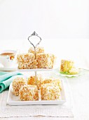 Lamingtons with white chocolate and grated coconut on a tiered cake stand