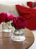 Romantisch rote Rosen in Glasväschen auf rustikalem Holztisch