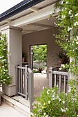 Climber-covered veranda with half-height, open gate and view into courtyard