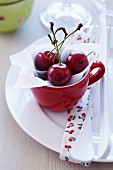 Freshly picked cherries in a red cup on a plate