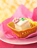Petit four in a yellow dish on pink paper