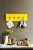 Hand-crafted yellow rack with hooks made from bent spoons on kitchen wall