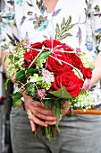 Hands holding bouquet with red roses
