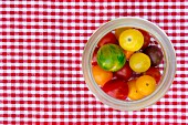 Fresh heirloom tomatoes in a preserving jar on a checked tablecloth